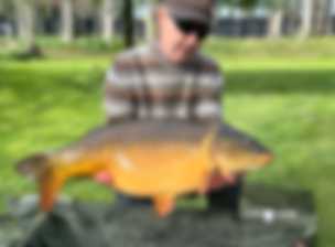 A kneeling fisherman poses with a fish he has caught A kneeling fisherman poses with a fish he has caught