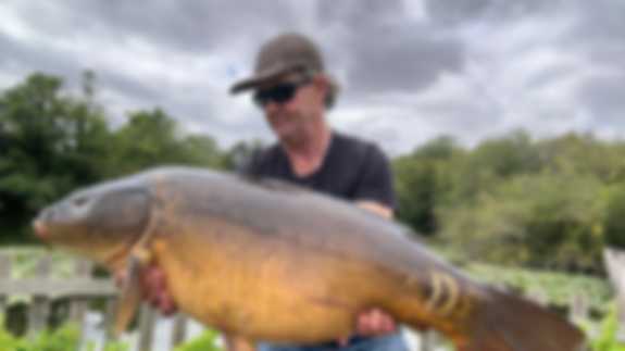 A fisherman poses with a lake record Mirror fish he has caught.