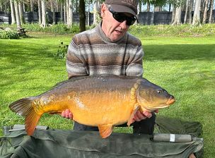 A kneeling fisherman poses with a fish he has caught