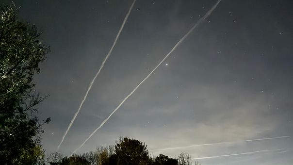 The night sky with stars and vapour trails from passing planes