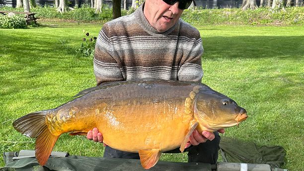 A fisherman poses with a 25lb+ Mirror fish.