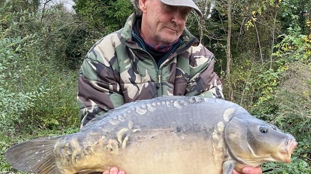 A fast-growing Mirror fish caught by a smiling fisherman.