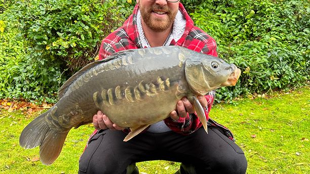 A person kneeling whilst holding a caught fish